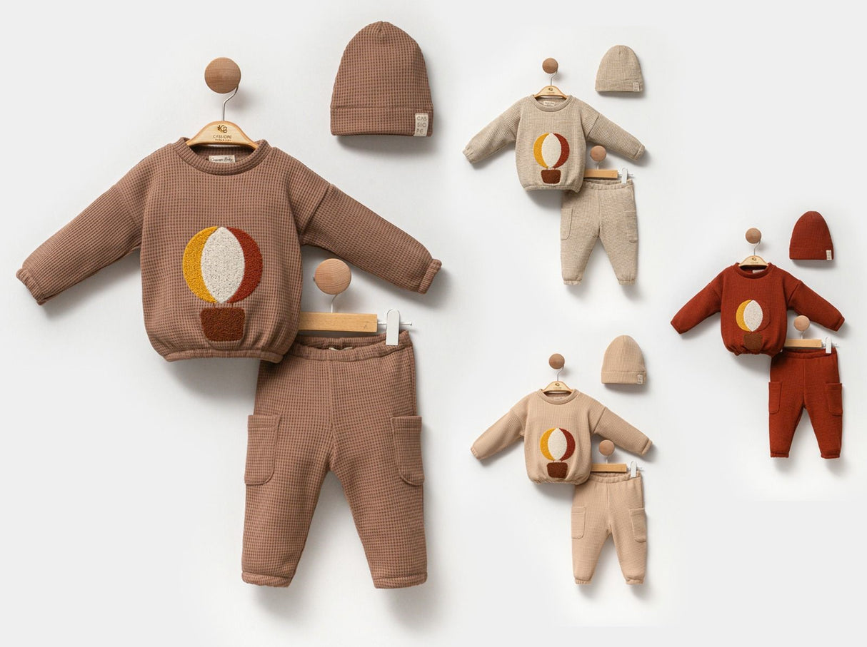 Ensemble bébé brun : sweat à motif bougie, pantalon et bonnet, avec autres tenues.