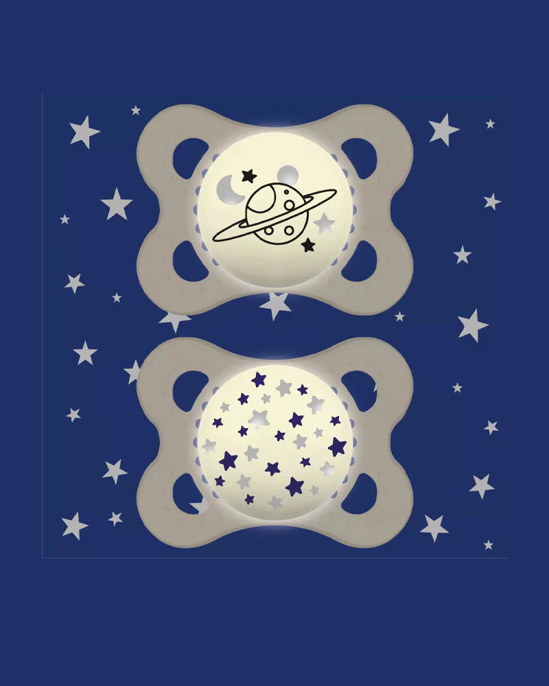 Deux sucettes MAM ivoire avec motifs planète et étoiles, anneaux ajourés.