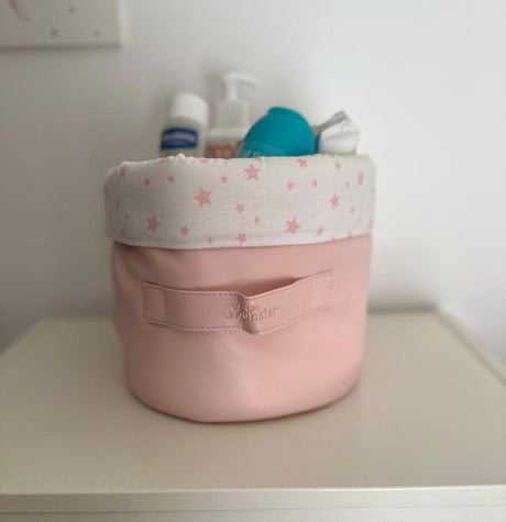Panier en tissu rose avec bord blanc à étoiles roses, contenant des articles