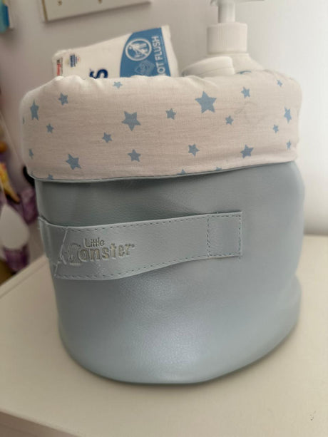 Panier rond gris clair, doublure blanche à étoiles bleues et étiquette Little Monsters